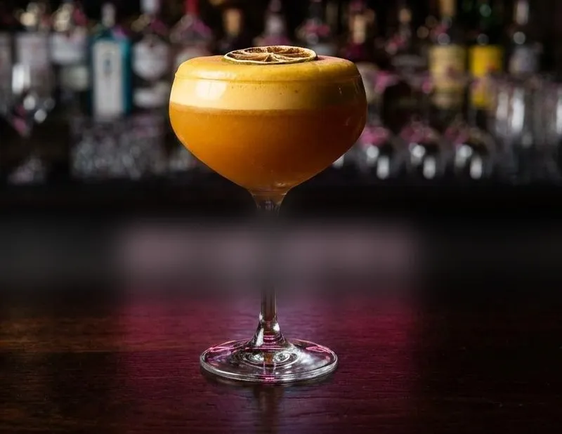 Bollywood Sour servido en copa coupé sobre la barra